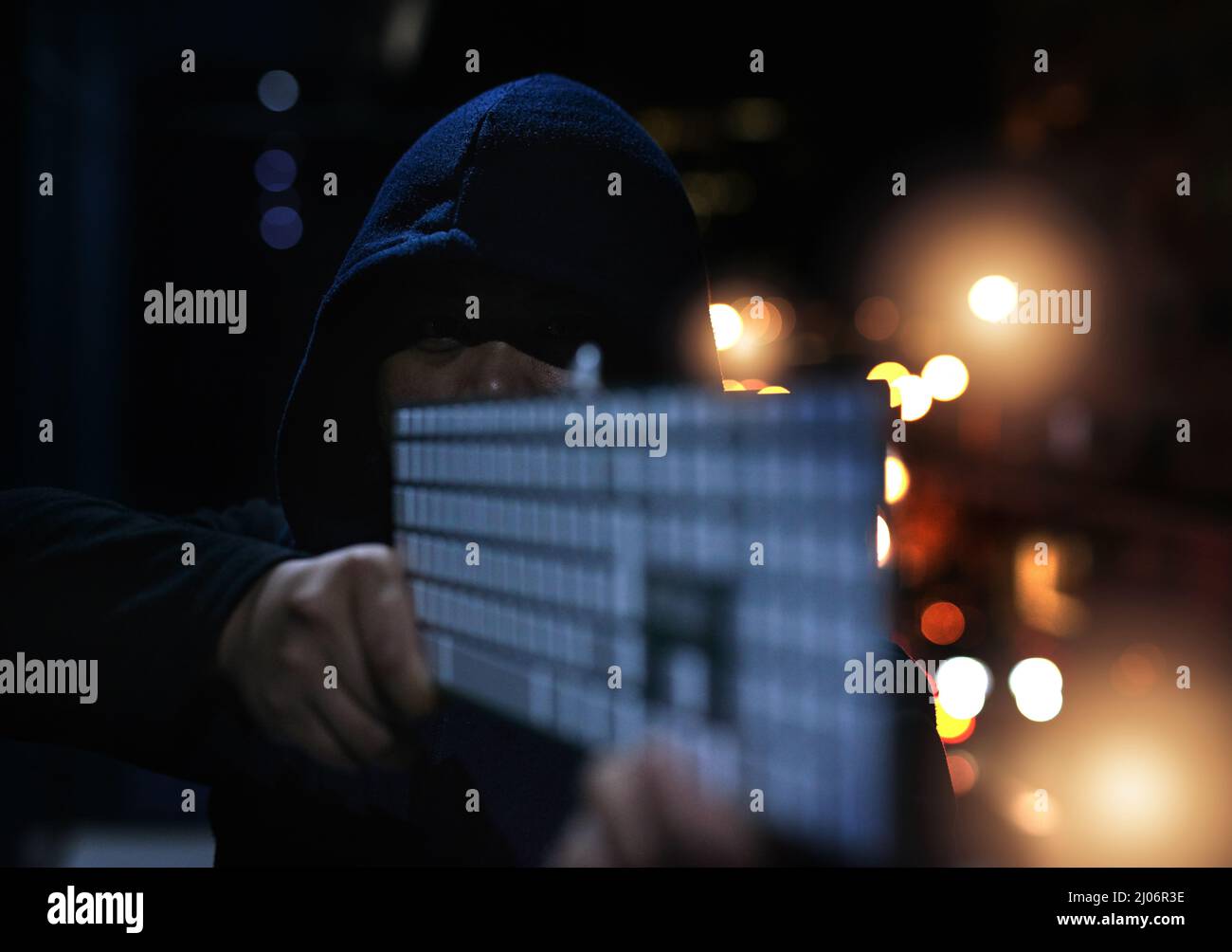 Armé et prêt à détruire vos données. Photo d'un pirate méconnaissable tenant un clavier dans l'obscurité. Banque D'Images