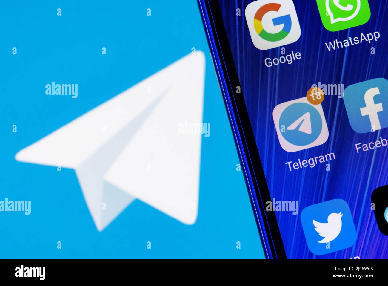 L'icône de l'application Telegram Messenger parmi d'autres applications sur l'écran du smartphone. En arrière-plan se trouve le logo Telegram. Banque D'Images