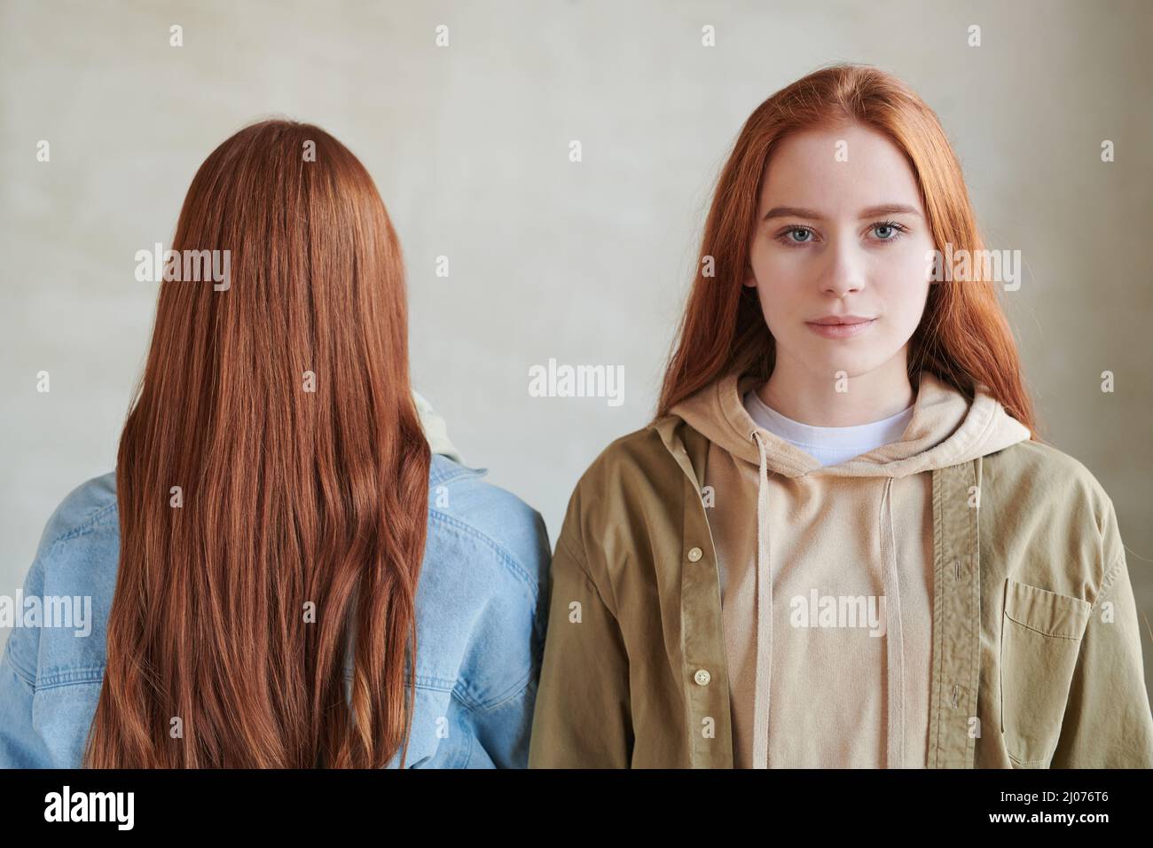 Portrait conceptuel horizontal moyen en gros plan de deux femmes aux cheveux rouges debout ensemble, l'une d'elles regardant l'appareil photo Banque D'Images