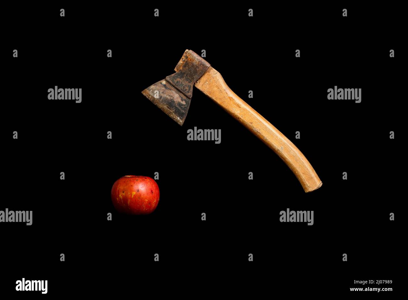 Vieille hache rouillée suspendue au-dessus de la pomme rouge sur un fond noir avec espace de copie Banque D'Images