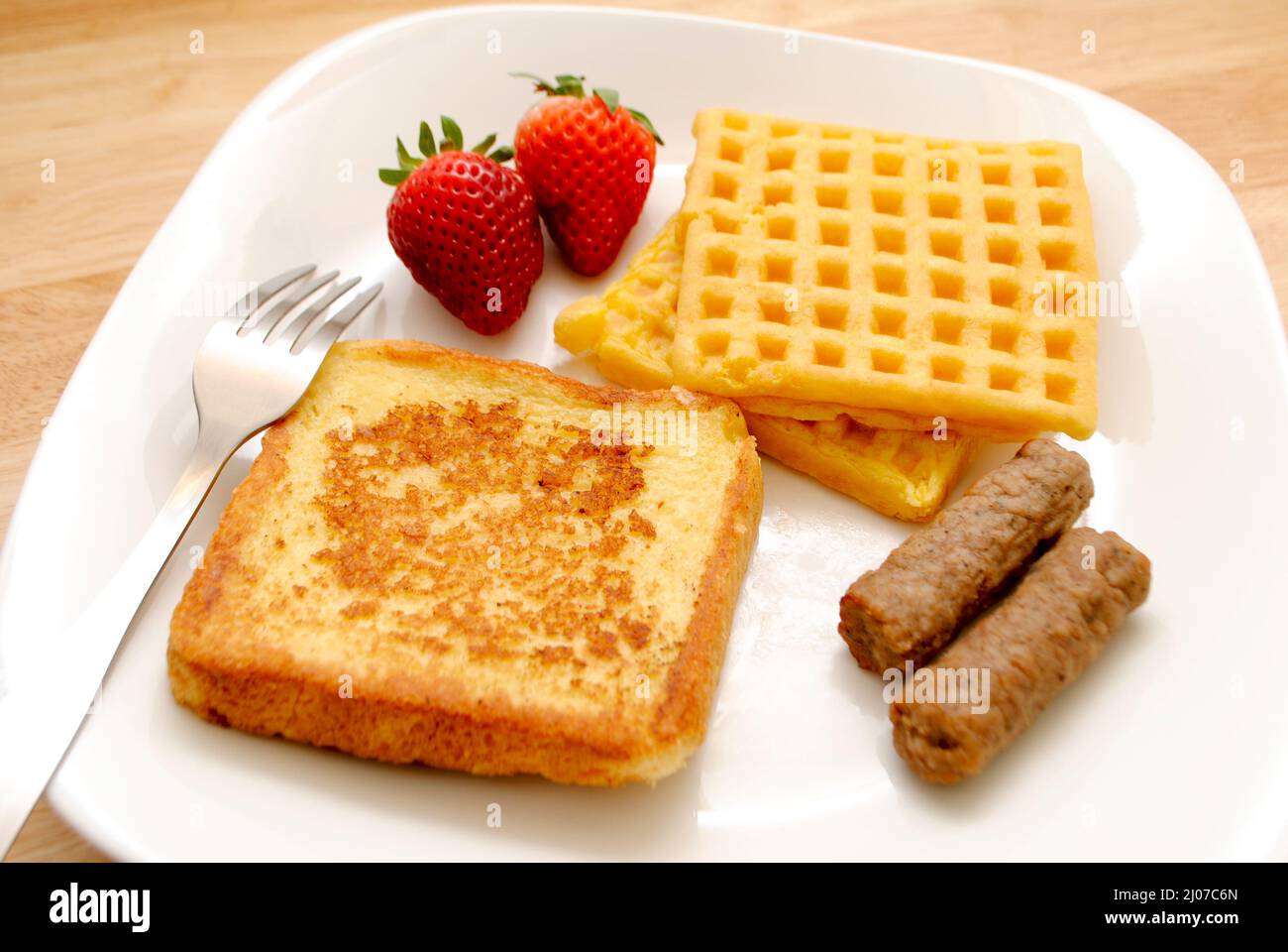 Pain grillé, gaufres et deux saucisses de porc sur une assiette blanche Banque D'Images