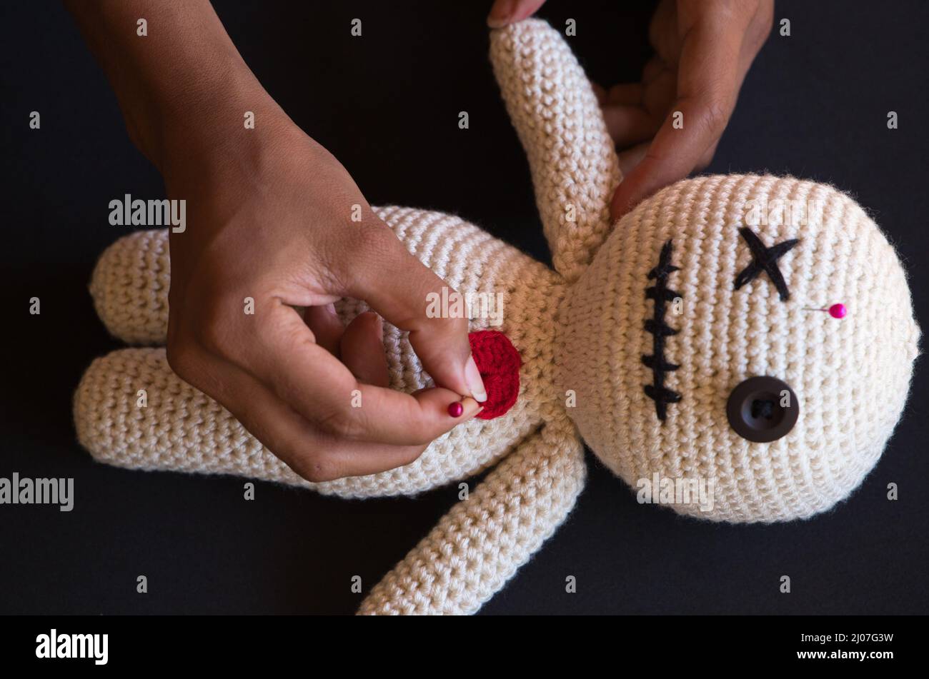Mains d'une sorcière faisant des rituels voodoo sur une poupée Banque D'Images