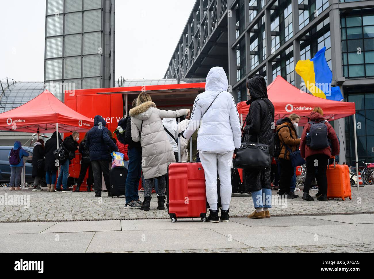Berlin, Allemagne. 17th mars 2022. Des réfugiés d'Ukraine font la queue devant la gare principale de Berlin pour obtenir des cartes SIM d'une voiture appartenant à la société de télécommunications Vodafone. Les réfugiés d'Ukraine reçoivent gratuitement une carte SIM pour leur smartphone pendant trois mois et peuvent ainsi rester en contact avec leur pays d'origine sans frais. Plusieurs milliers de personnes arrivent chaque jour à la gare de la capitale allemande et le nombre de réfugiés d'Ukraine devrait continuer d'augmenter. Credit: Bernd von Jutrczenka/dpa/Alamy Live News Banque D'Images