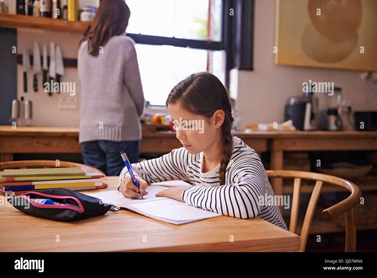 Shes haut de sa classe pour une raison. Une jeune fille occupée faisant ses devoirs à la table de cuisine. Banque D'Images