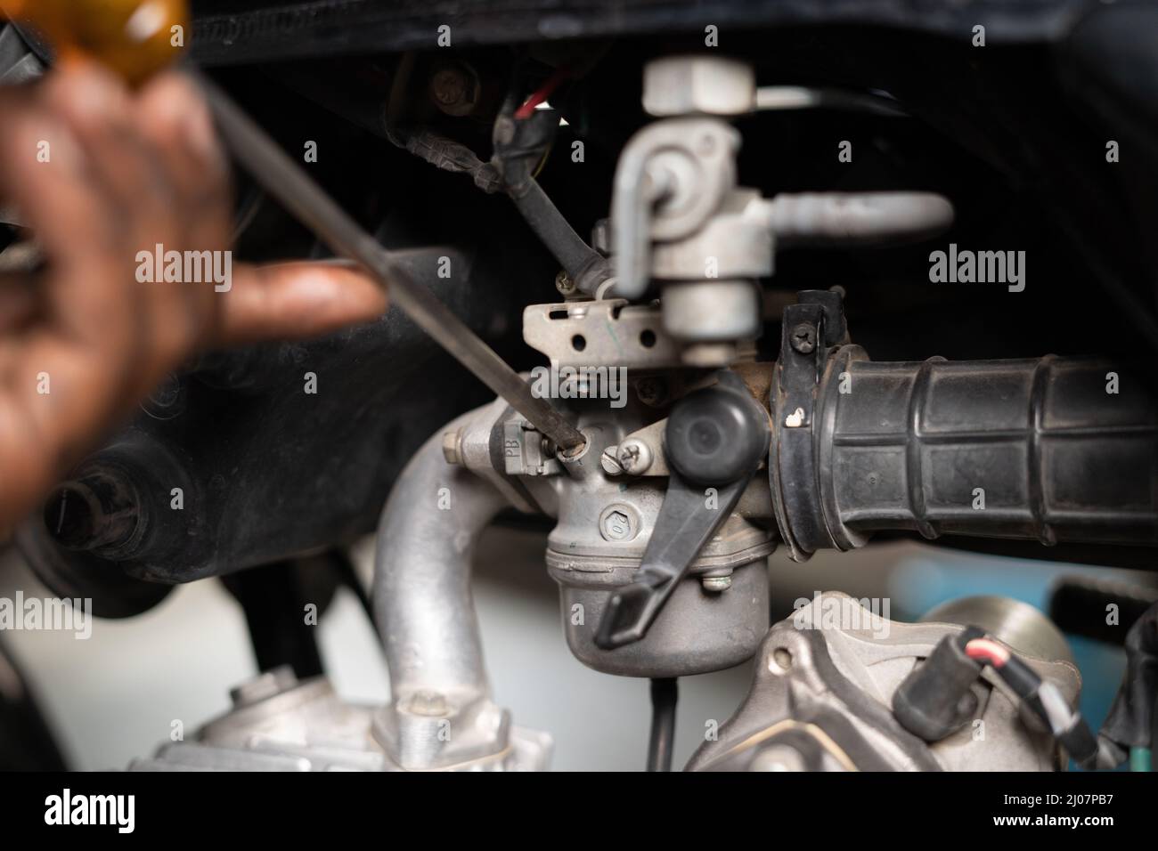 Gros plan d'un mécanicien chargé de réparer le filtre à air de moto dans un garage - concept de service de réparation et d'entretien. Banque D'Images