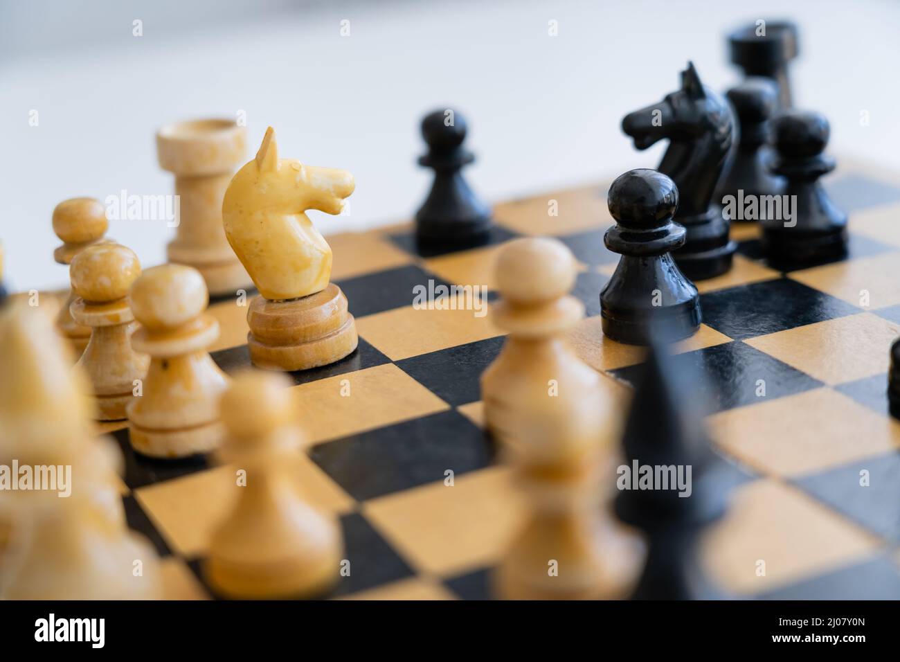 Figures d'échecs en bois sur échiquier sur fond blanc Banque D'Images