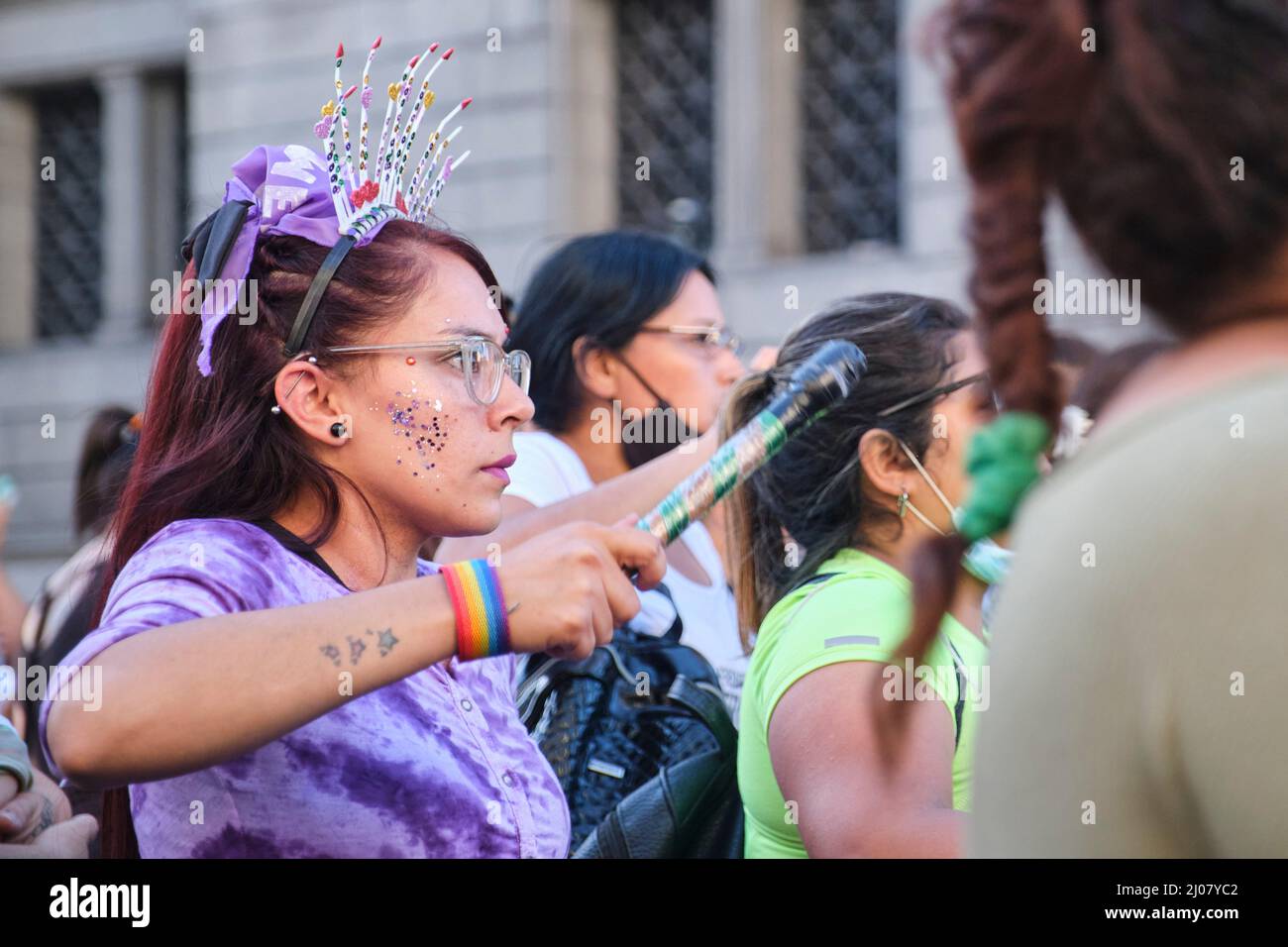Buenos Aires, Argentine; 8 mars 2022: Grève féministe. Femme marchant et jouant de la musique avec un foulard violet, symbole de la lutte féministe, et un Banque D'Images