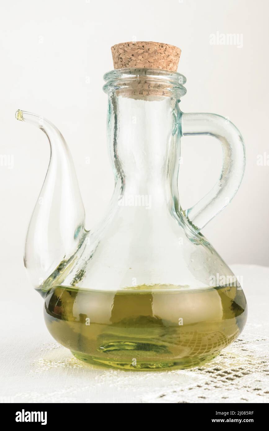 Huile d'olive extra vierge dans un pot rustique en verre sur une table de cuisine vintage. Image verticale. Banque D'Images