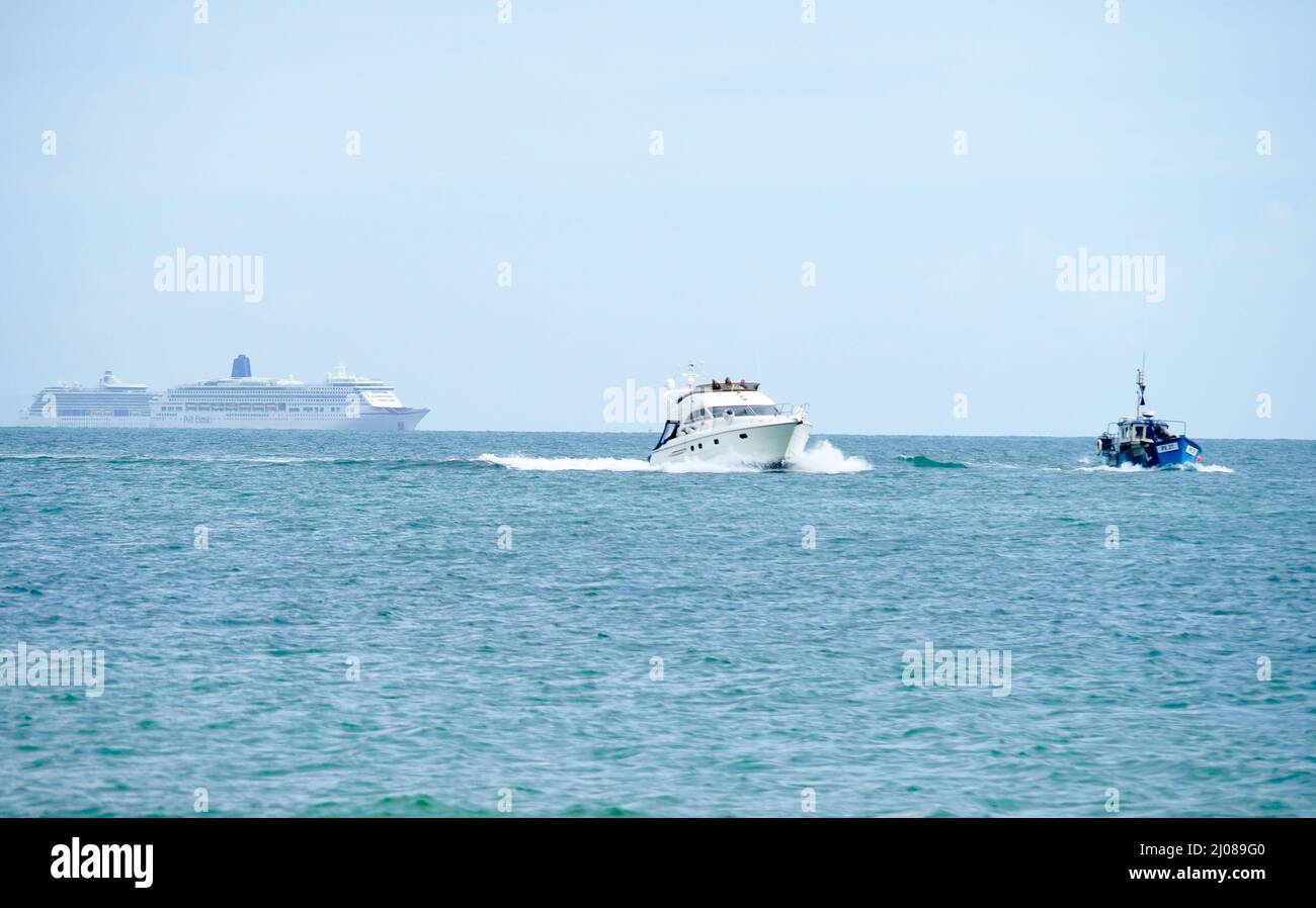 Un petit bateau de pêche et un bateau à moteur avec deux grands paquebots de croisière amarrés en arrière-plan en mer Banque D'Images