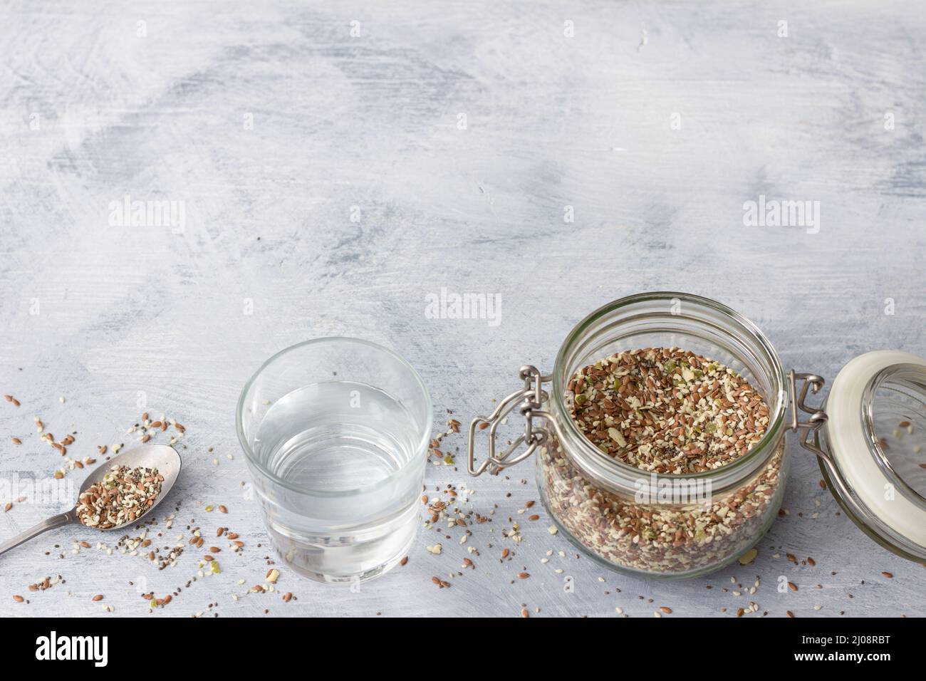 Mélange de céréales pour des craquelins keto sains de graines de chia, de lin, de sésame, de graines de citrouille moulues dans un pot en verre sur fond de bois gris, horizontal Banque D'Images