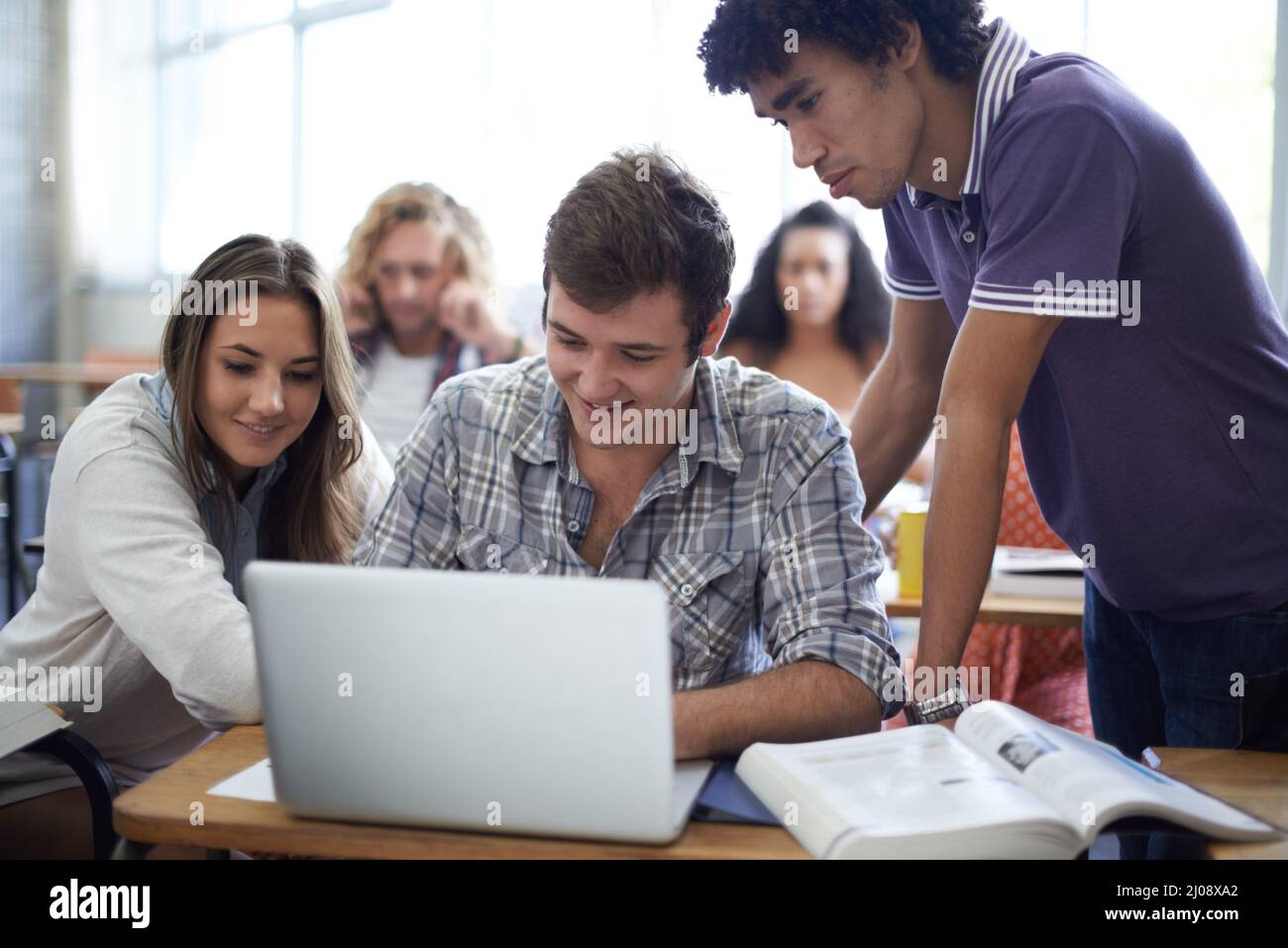 Utiliser chaque ressource pour leur projet. Photo d'un groupe d'étudiants universitaires travaillant sur des ordinateurs portables en classe. Banque D'Images