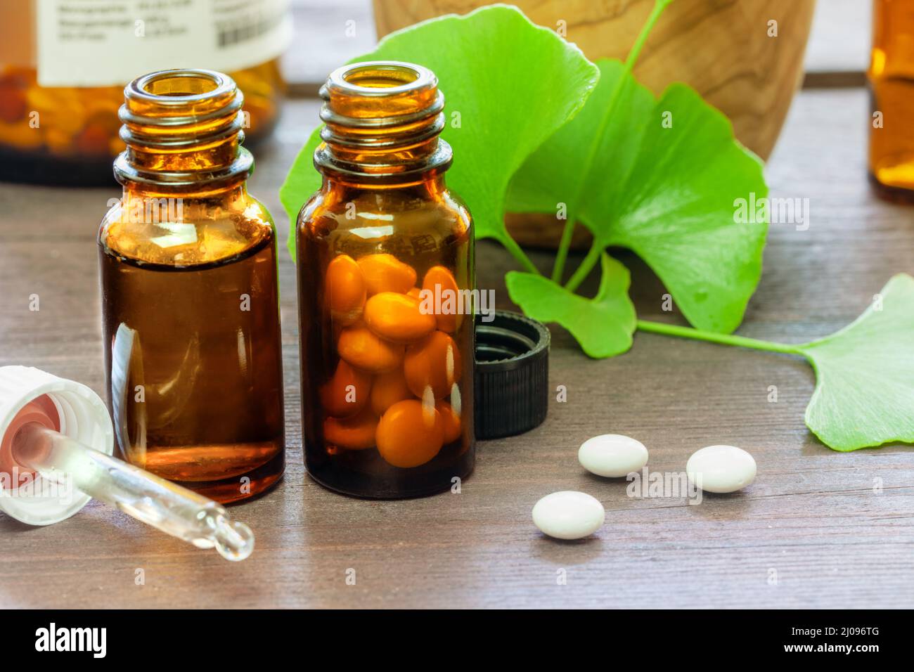 Flacon de pipette, pilules et feuilles de ginkgo décorées sur fond de bois. Concept homéopathique. Banque D'Images