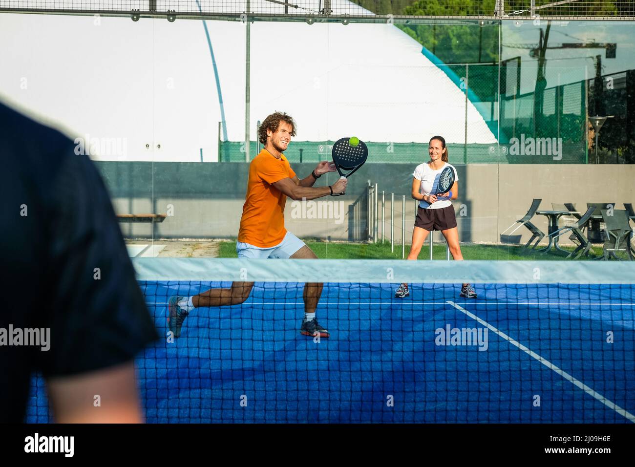 L'entraîneur enseigne aux jeunes comment jouer au padel sur un court de tennis extérieur - Mixte padel Match outdoorin un terrain de padel d'herbe bleue - Sport et amis conc Banque D'Images
