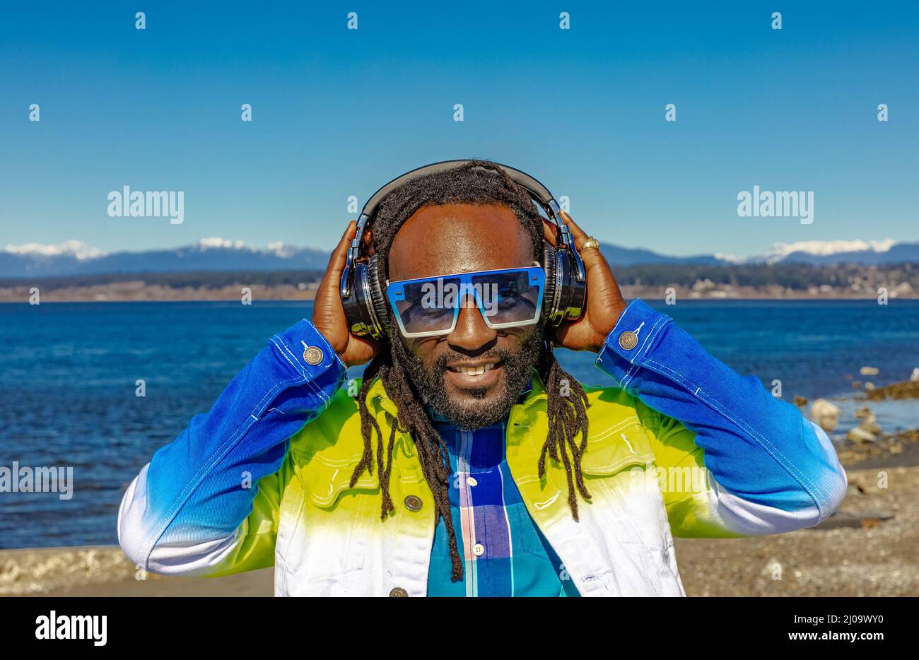 Beau jeune homme afro-américain attrayant avec des dreadlocks écoutant de la musique en plein air. Photo de rue. White Rock C.-B., Canada-mars 3,2022 Banque D'Images