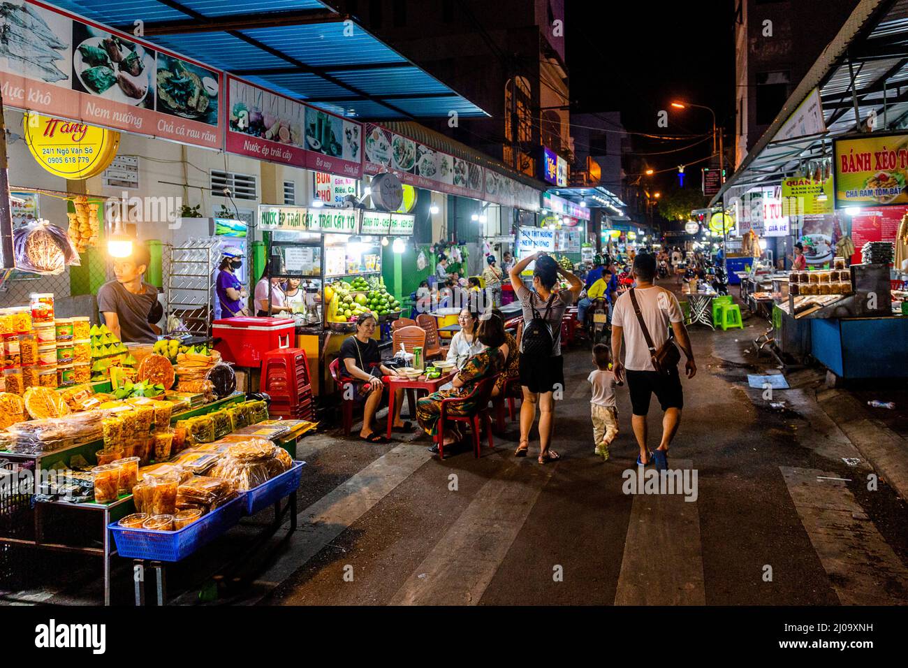 Street food et marché de nuit à Quy Nhon. Une famille descend au milieu de la rue pour faire du shopping et regarder autour. Banque D'Images