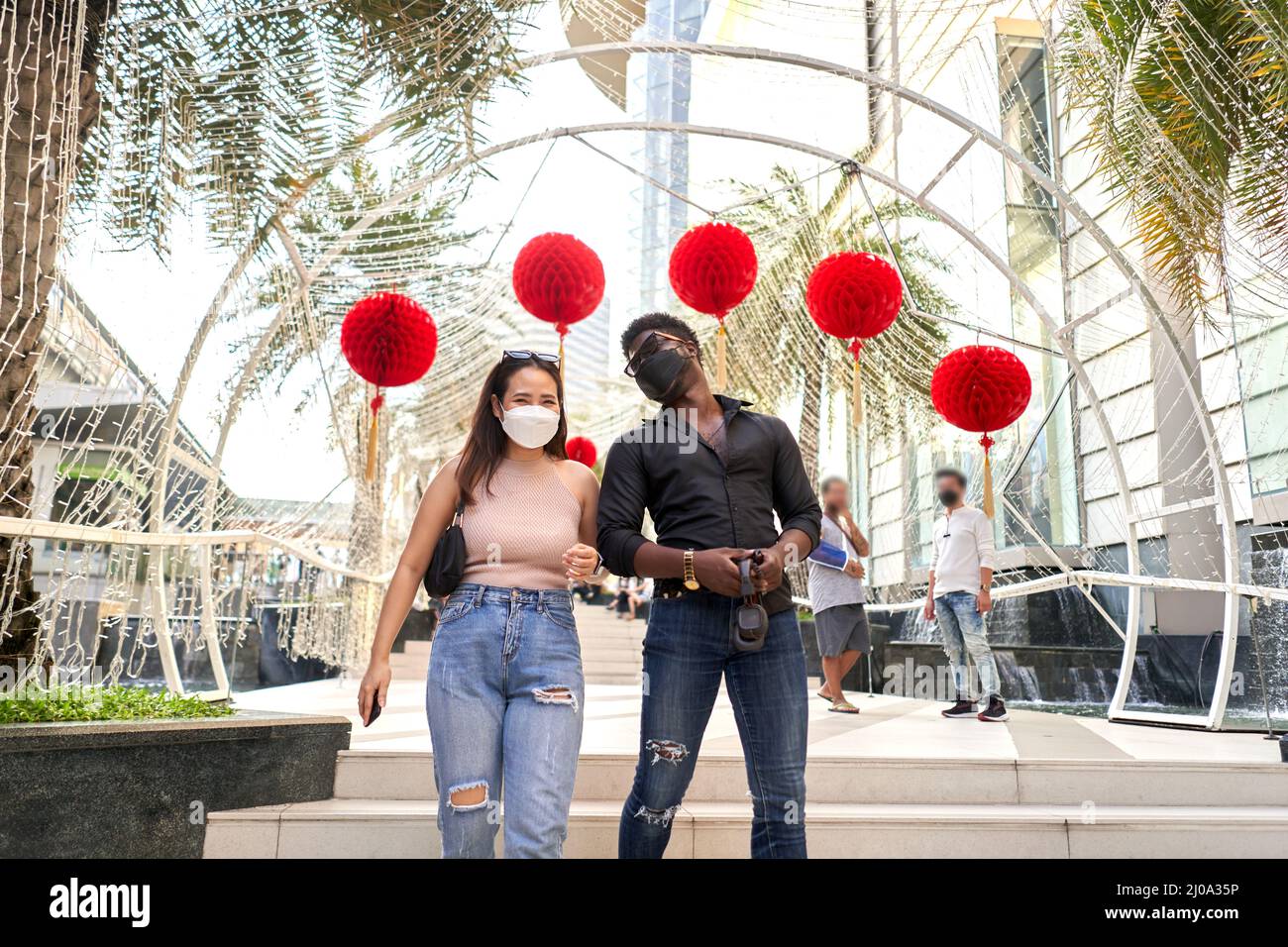 Deux amis multiraciaux portant un masque facial marchant dans un centre commercial Banque D'Images