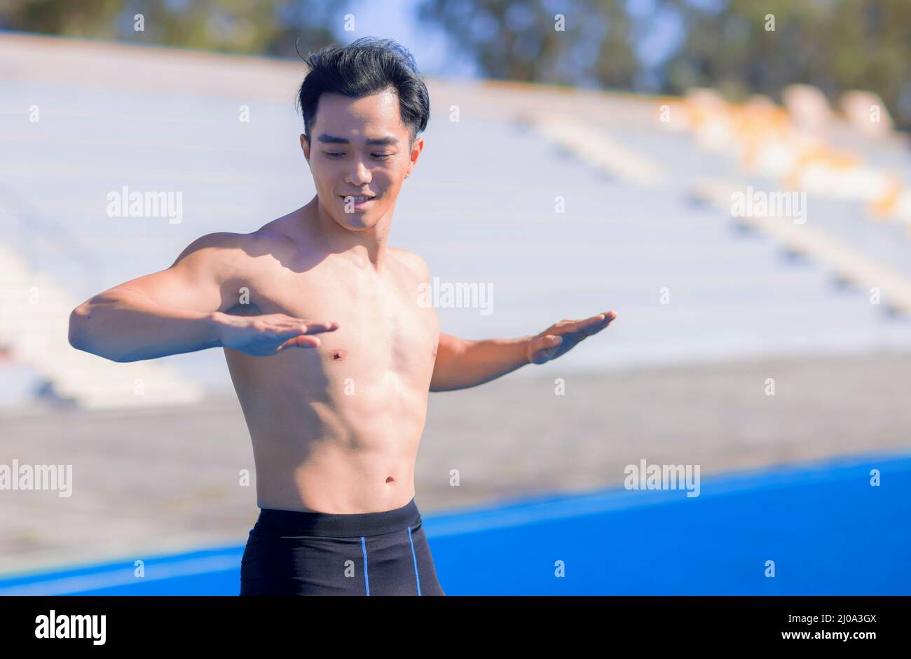 Jeune homme en forme avec des muscles étirant et se réchauffant avant l'entraînement à l'extérieur Banque D'Images