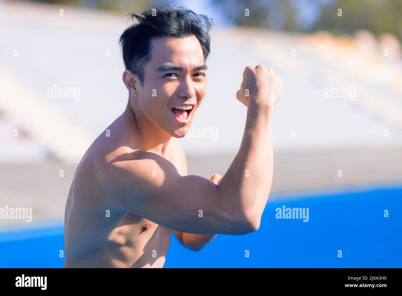 Jeune homme de forme excité avec les muscles s'étirant et se réchauffant avant l'entraînement à l'extérieur Banque D'Images