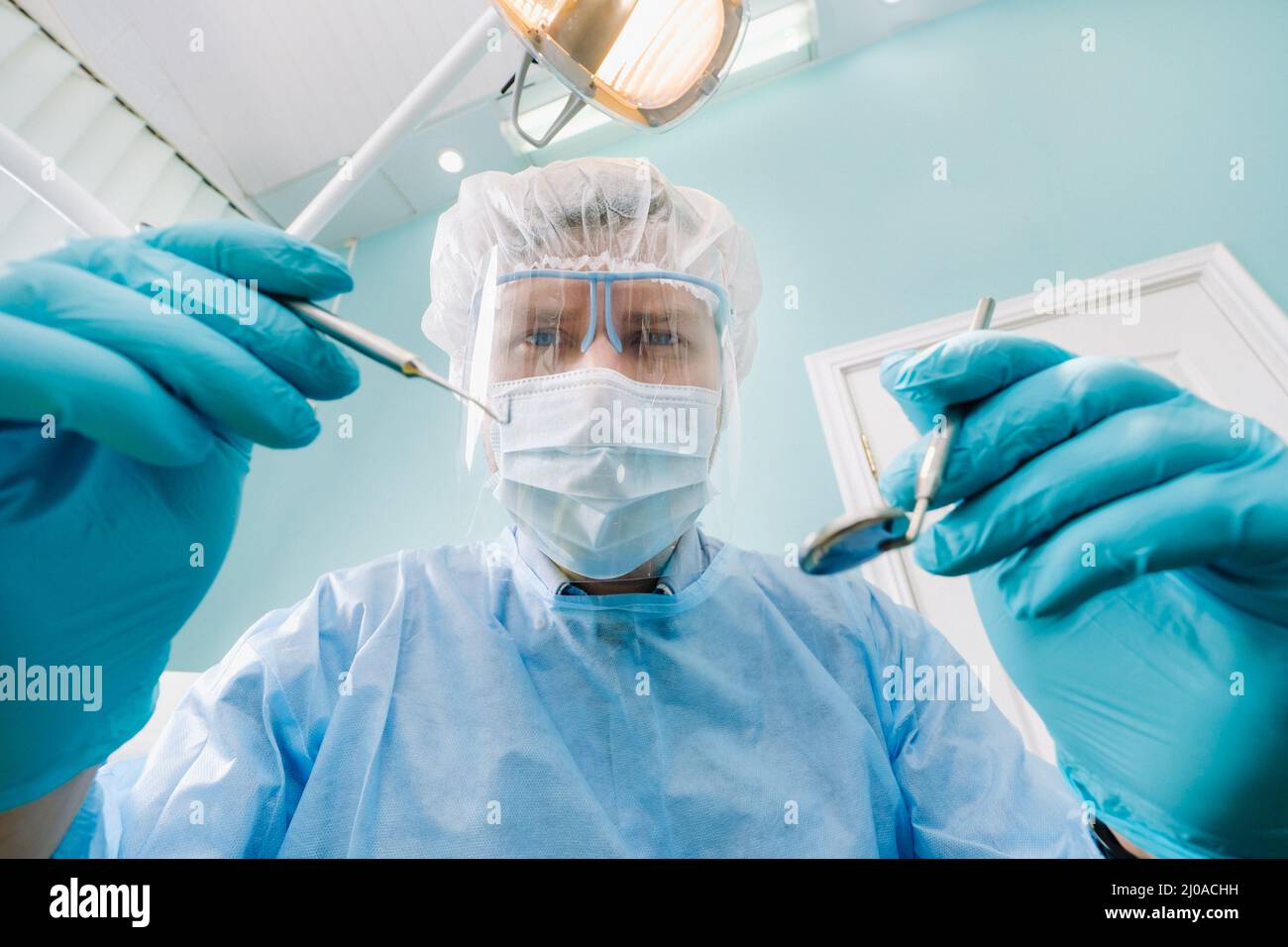 un dentiste portant un masque de protection se trouve à proximité et tient  les instruments dans ses mains avant de traiter un patient dans le cabinet  dentaire Photo Stock - Alamy