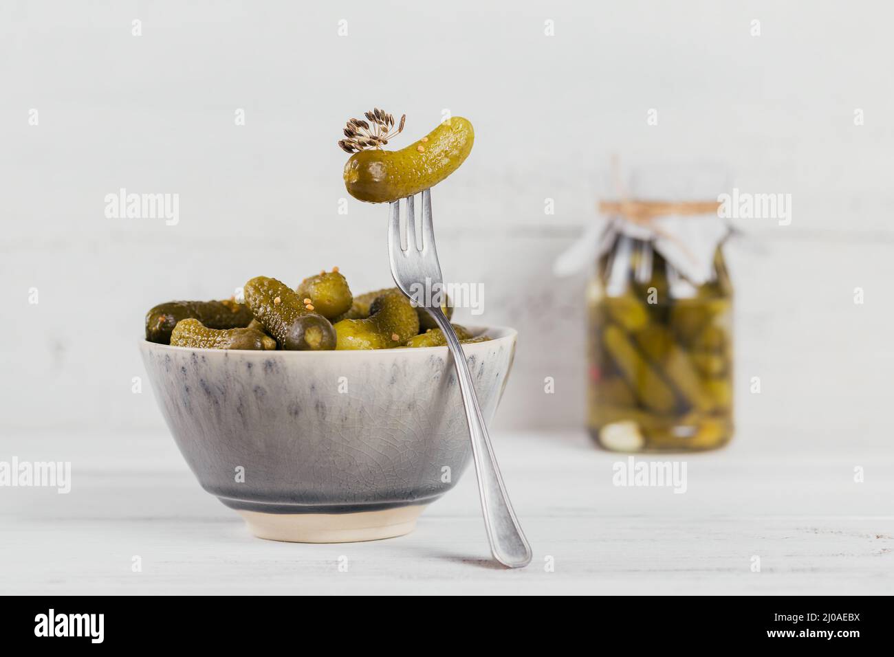 Conserver les concombres marinés, les assaisonnements et l'ail sur une table en bois blanc. Aliments fermentés sains. Légumes en conserve à la maison. Banque D'Images