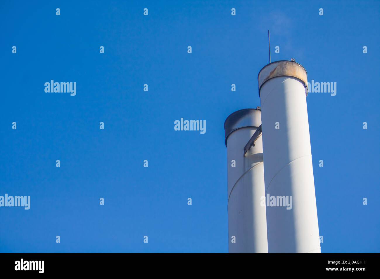 Cheminées d'une centrale à granulés de bois pour l'approvisionnement en chauffage local devant le ciel bleu Banque D'Images