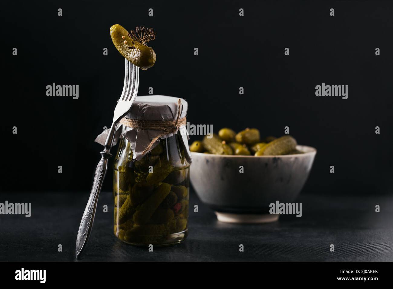 Conserver les concombres marinés, les assaisonnements et l'ail sur une table sombre. Aliments fermentés sains. Légumes en conserve à la maison. Banque D'Images