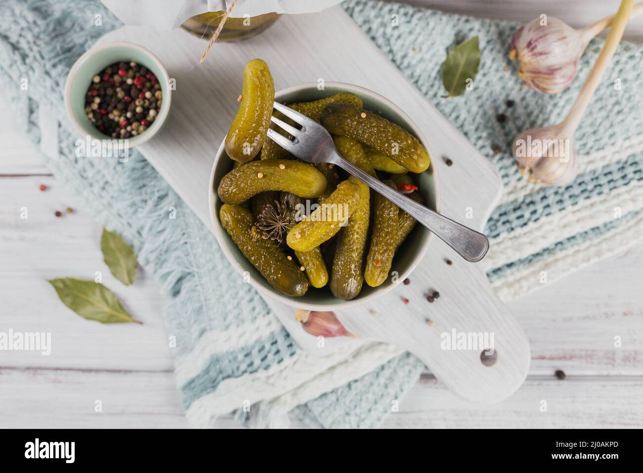 Cornichons, concombre mariné sur une fourchette, bol de légumes marinés sur fond de bois blanc. Cuisine propre, concept végétarien. Vue de dessus, fermer Banque D'Images