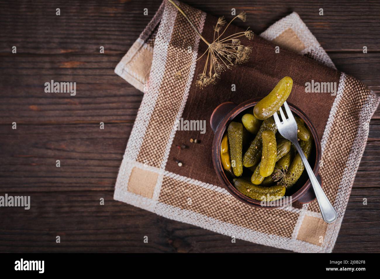 Conserver les concombres marinés, les assaisonnements et l'ail sur une table en bois sombre. Aliments fermentés sains. Légumes en conserve à la maison. Banque D'Images