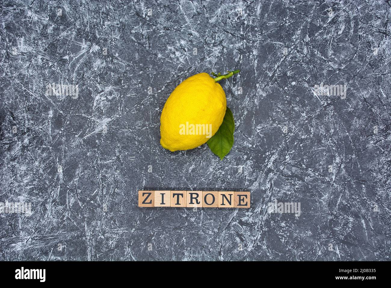Gros plan d'un citron mûr isolé sur fond texturé gris. Banque D'Images