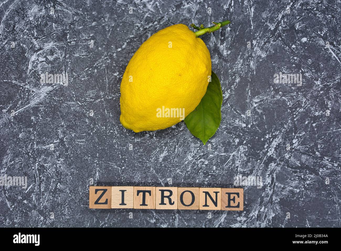 Gros plan d'un citron mûr isolé sur fond texturé gris. Banque D'Images