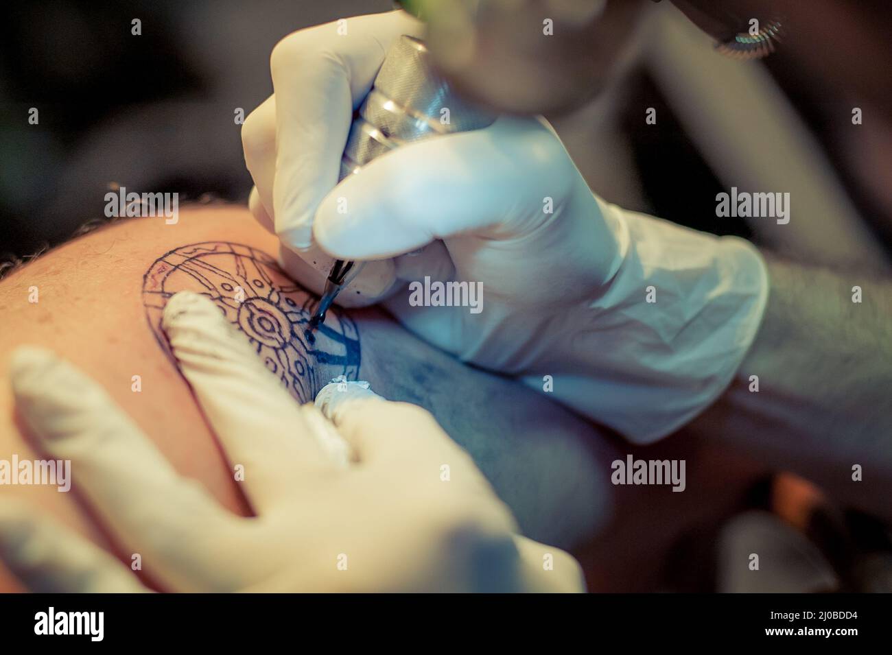 Le tatouage maître dessine la peinture bleue sur le tatouage client Banque D'Images