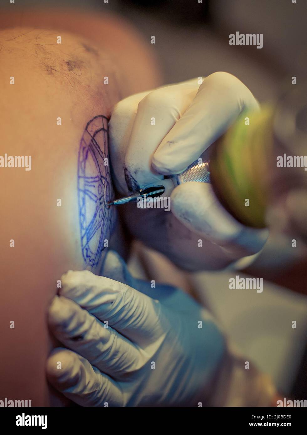 Le tatouage maître dessine la peinture bleue sur le tatouage client Banque D'Images