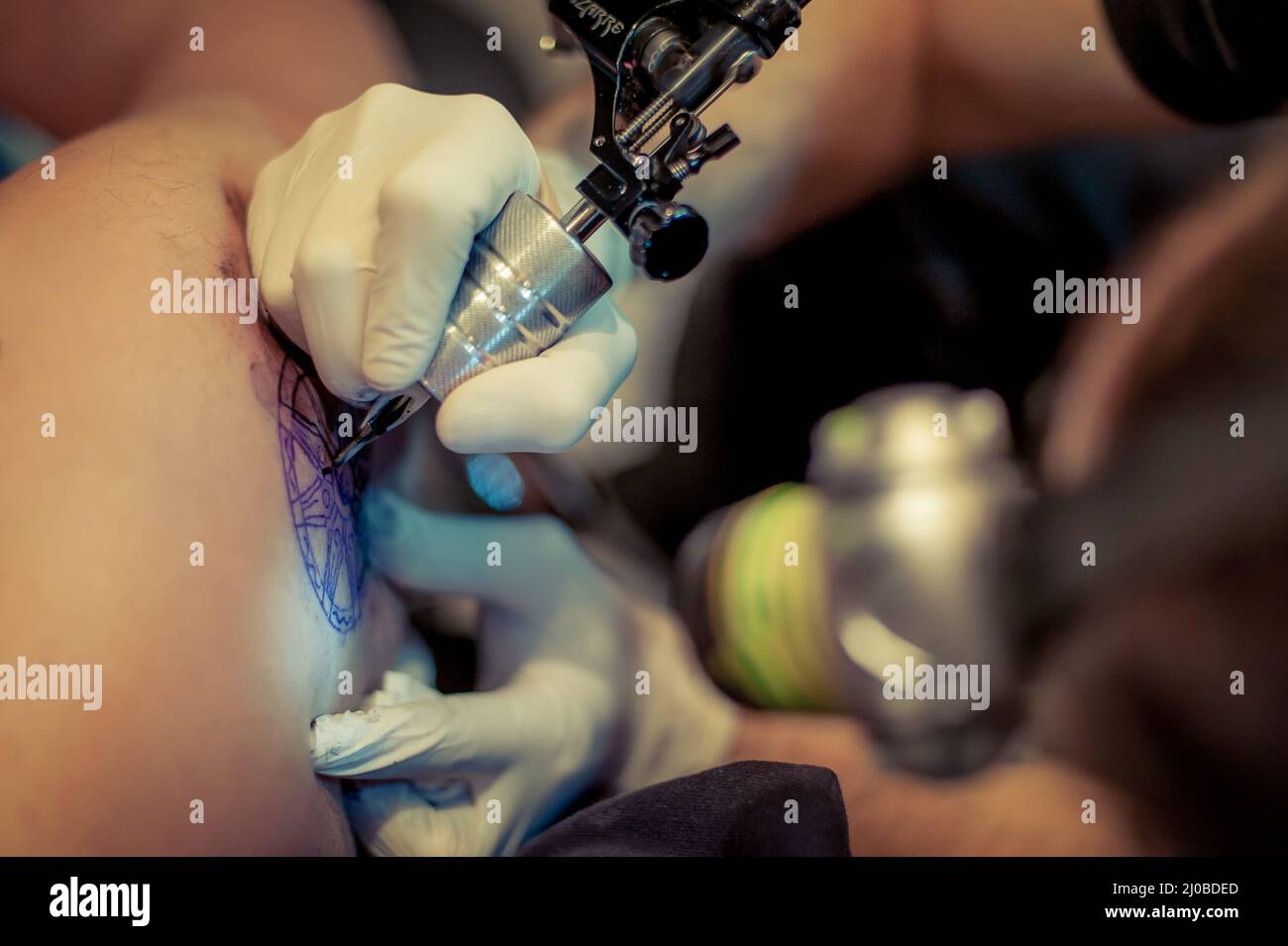 Le tatouage maître dessine la peinture bleue sur le tatouage client Banque D'Images