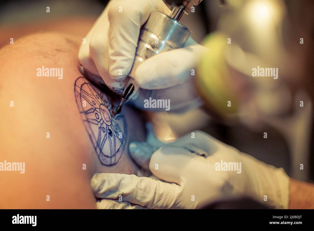 Le tatouage maître dessine la peinture bleue sur le tatouage client Banque D'Images