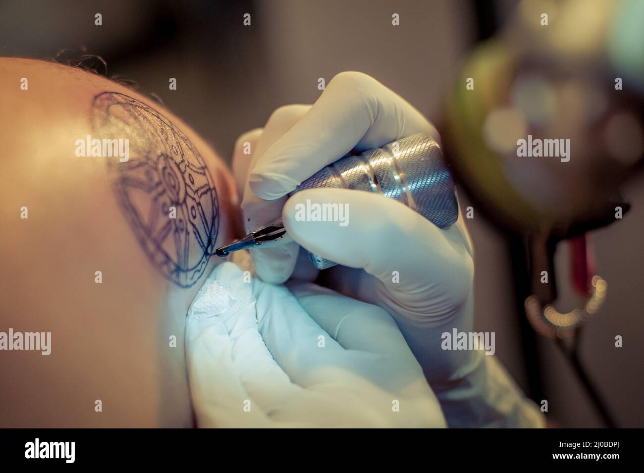 Le tatouage maître dessine la peinture bleue sur le tatouage client Banque D'Images