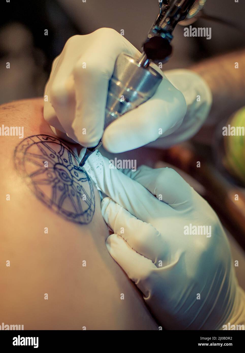 Le tatouage maître dessine la peinture bleue sur le tatouage client Banque D'Images