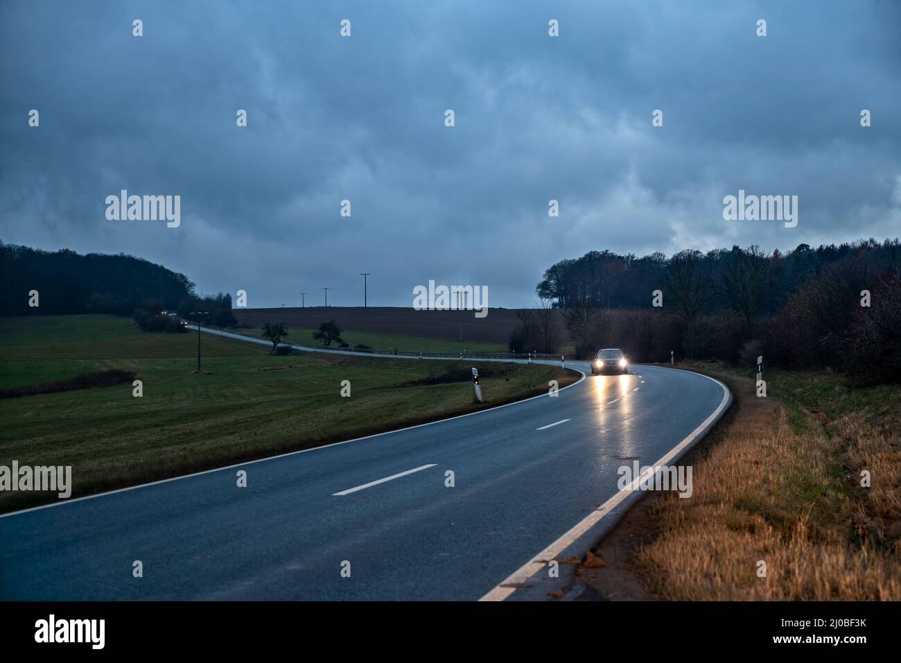 Voiture sur une route de campagne près de Wehrheim im Taunus (Allemagne) au crépuscule Banque D'Images
