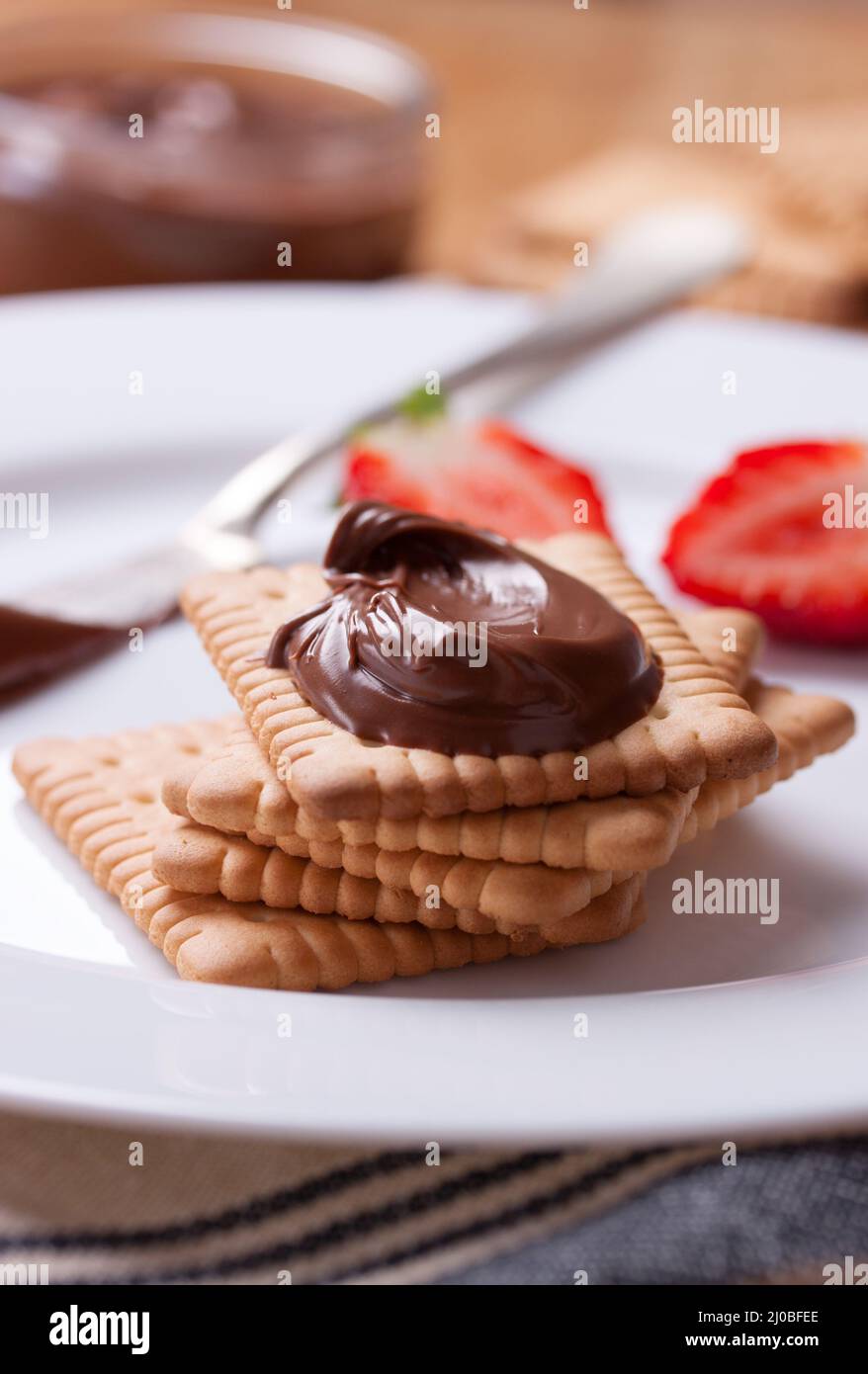 Crème de nougat douce au chocolat sur des biscuits et des fraises sur une assiette blanche. Gros plan Banque D'Images