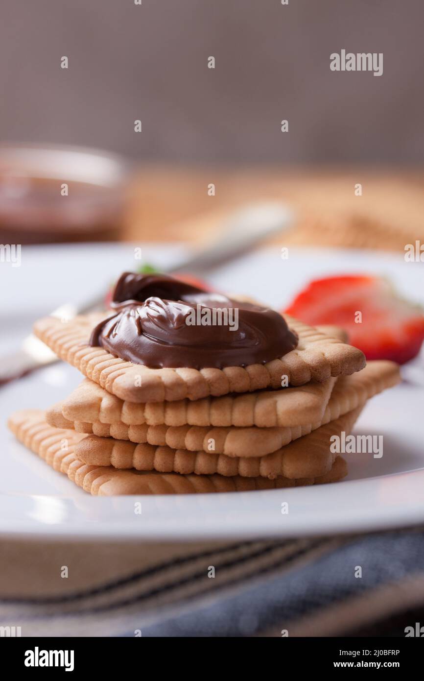 Crème de nougat douce au chocolat sur des biscuits et des fraises sur une assiette blanche Banque D'Images