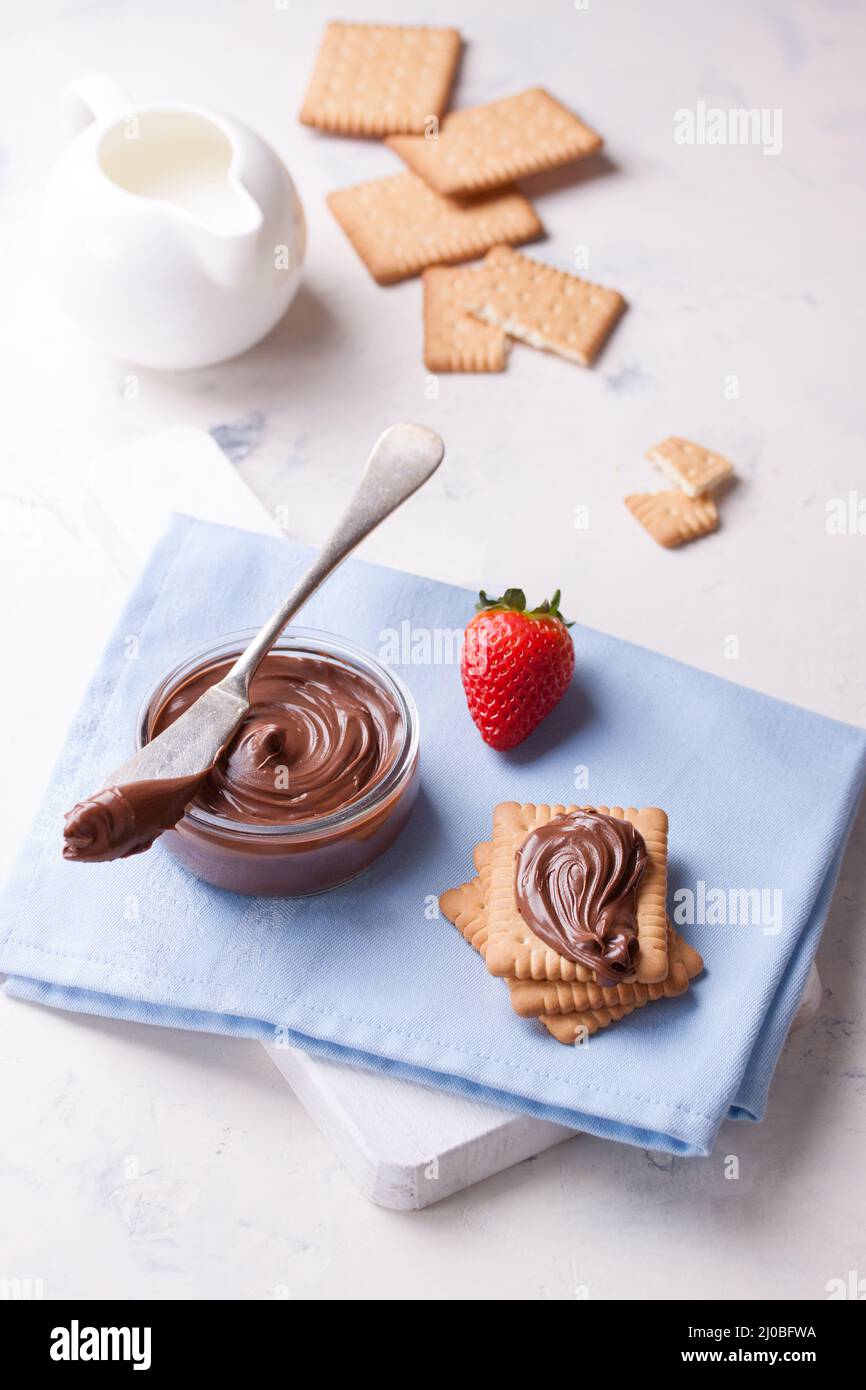 Crème de nougat douce au chocolat sur des biscuits et des fraises sur une assiette blanche Banque D'Images