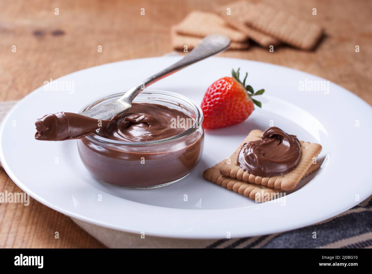 Crème de nougat douce au chocolat sur des biscuits et des fraises sur une assiette blanche. Gros plan Banque D'Images