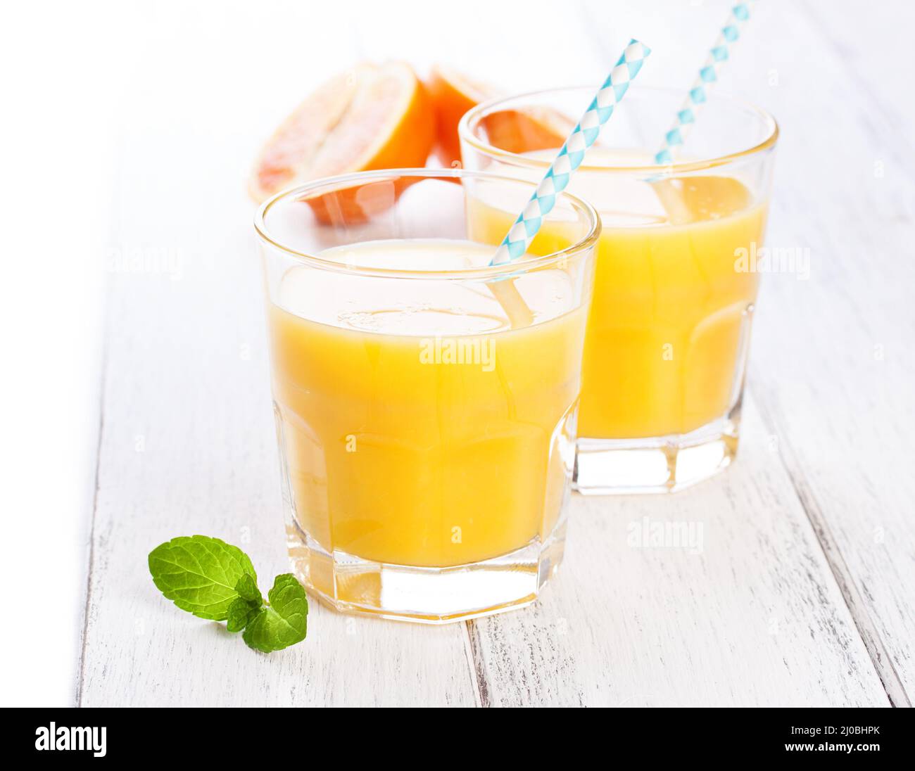 Limonade orange jaune d'été en verre avec des oranges sanguines et de la paille sur une table en bois Banque D'Images