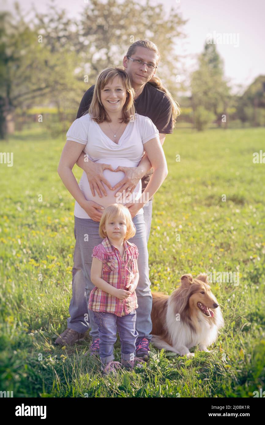 Femme enceinte et son mari avec sa fille tenant ses mains en forme de coeur sur son bébé Photo