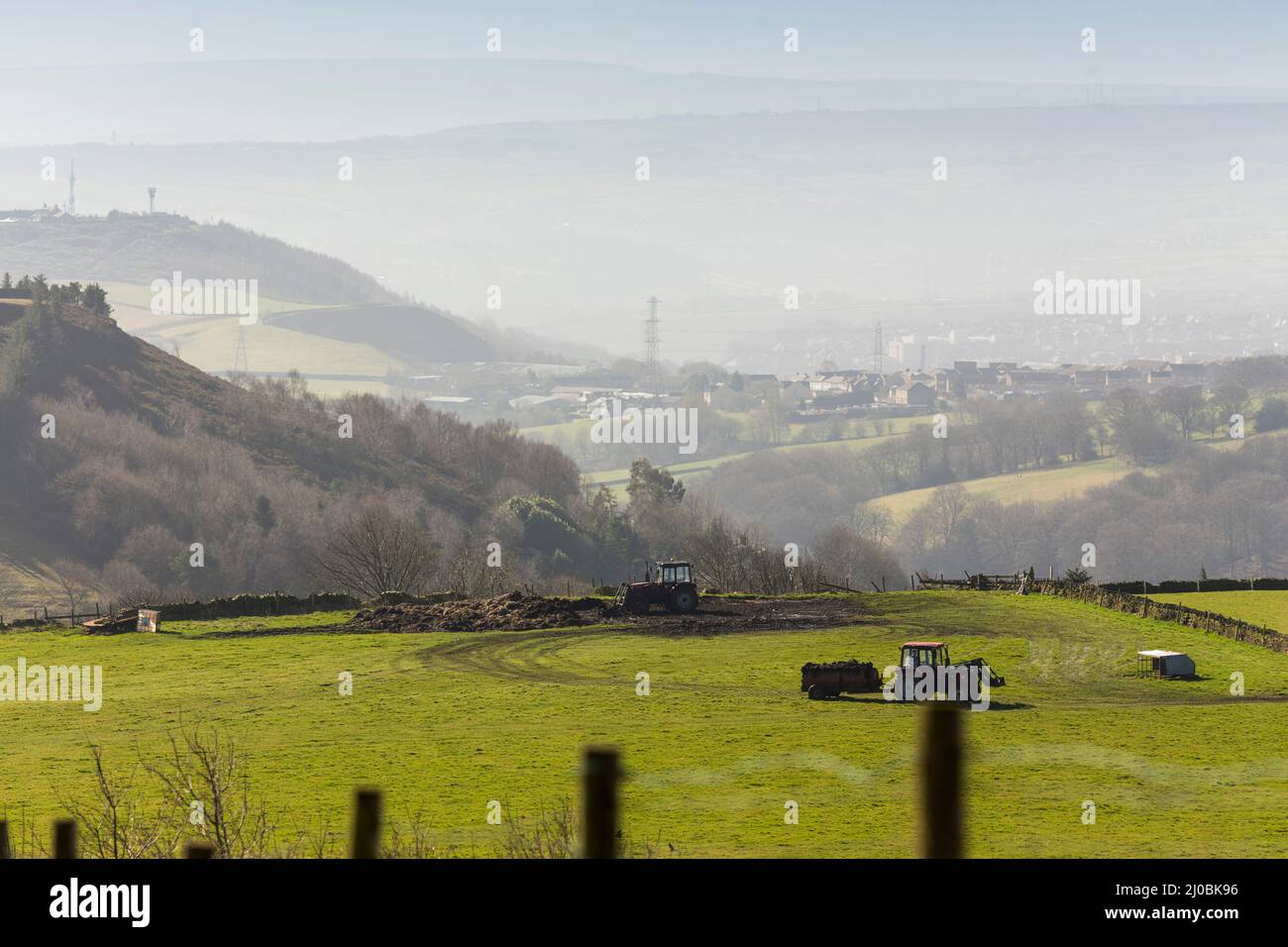 Halifax, West Yorkshire, Royaume-Uni. 17th mars 2022. Météo Royaume-Uni. Une nuit de gel a laissé place à un magnifique ciel bleu à Halifax, West Yorkshire, Royaume-Uni. Dans la vallée de Shibden, un agriculteur prépare ses champs pour la quatrième saison d'épandage de fumier pour nourrir l'herbe. La vallée de Shibden est connue pour être l'ancienne maison d'Anne Lister sérialisée dans le monsieur Jack de production TV. Crédit : Windmill Images/Alamy Live News Banque D'Images