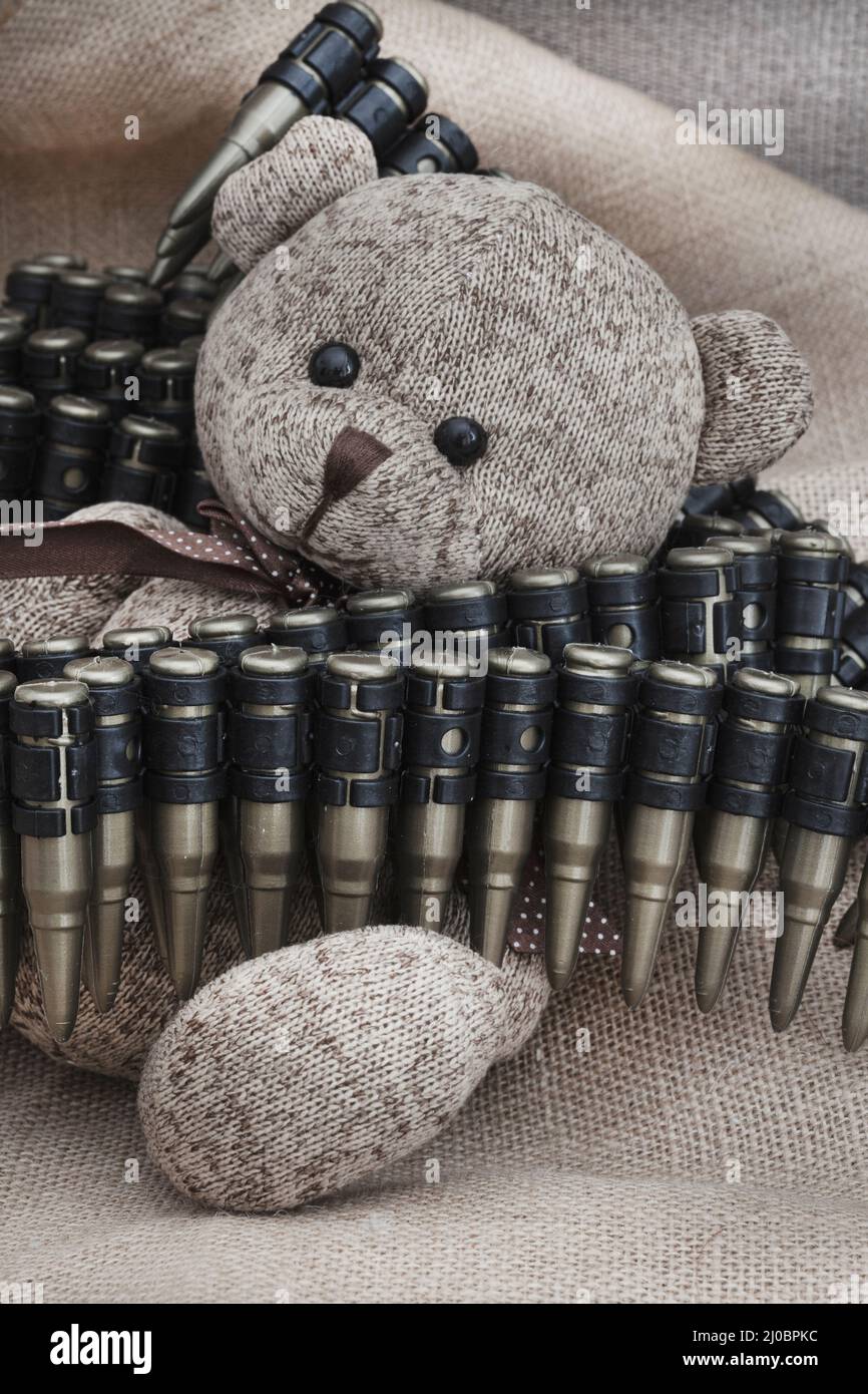 ours en peluche de style rustique sur un tissu hessien et rugueux avec des jouets de guerre, illustrant une enfance pendant une période de guerre Banque D'Images