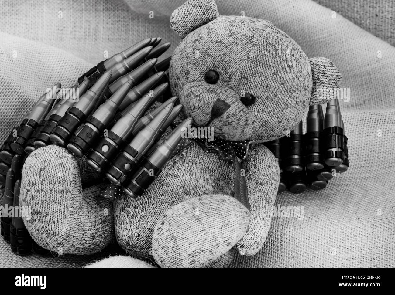 ours en peluche de style rustique sur un tissu hessien et rugueux avec des jouets de guerre, illustrant une enfance pendant une période de guerre Banque D'Images