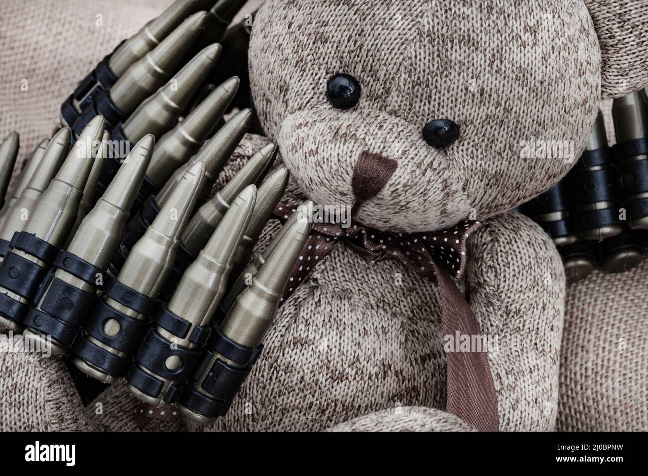 ours en peluche de style rustique sur un tissu hessien et rugueux avec des jouets de guerre, illustrant une enfance pendant une période de guerre Banque D'Images