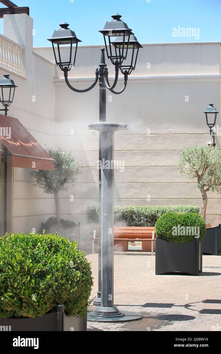 Les gicleurs éclaboussant de l'eau vaporisée dans la rue afin de refroidir la température estivale chaude Banque D'Images