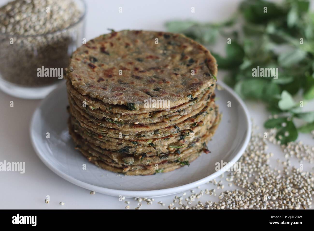 Bajra methi thepla. Pain plat indien fait de farine de millet perlé, feuilles de fenugrec, graines de sésame, yaourt et épices. Prise de vue sur fond blanc. Banque D'Images