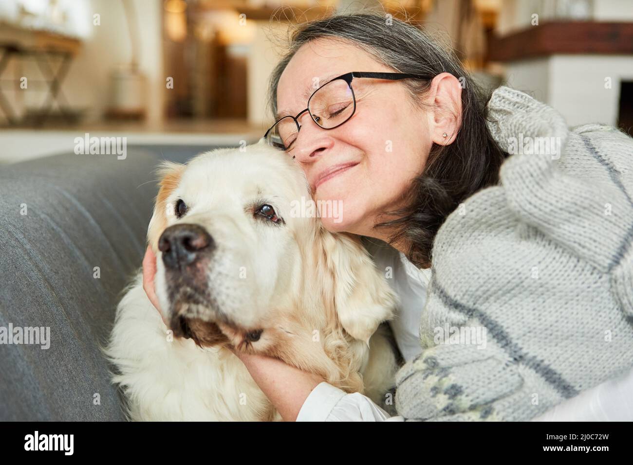 La vieille femme se coud avec son chien sur le canapé à la maison contre la solitude et pour l'amitié Banque D'Images